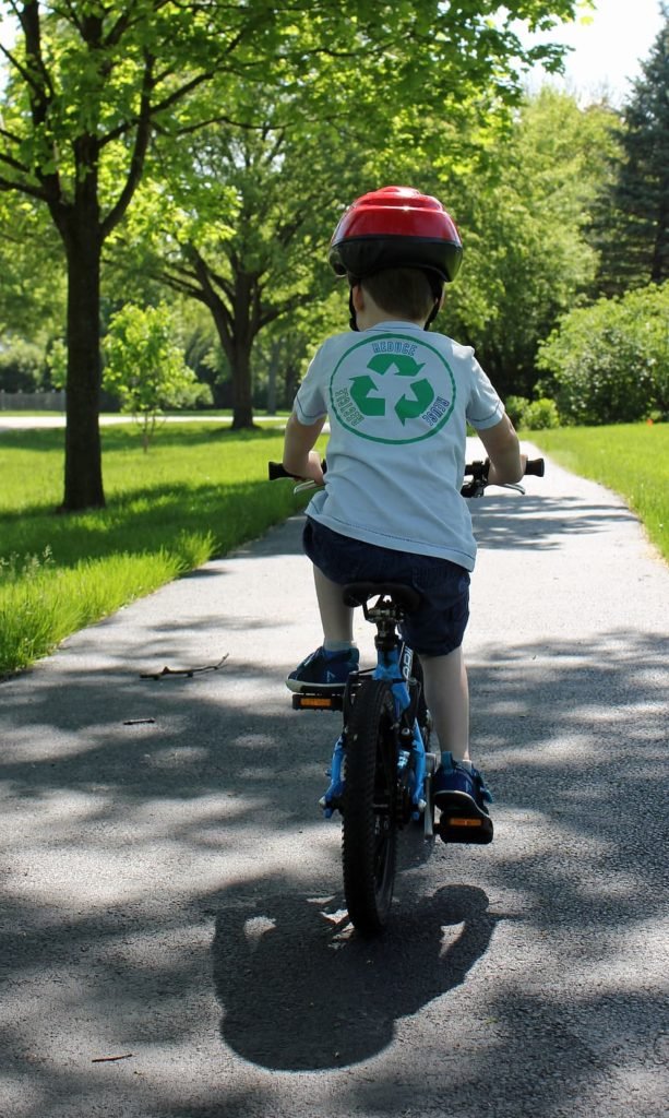 Shows a young boy riding a bike through the park. Fundamental skills of balance, control, and strength are used.